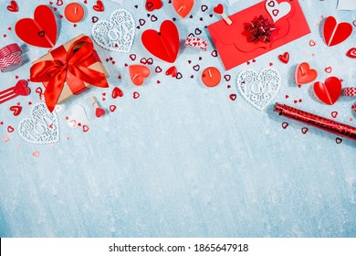 Greeting card for Valentine's Day. Red hearts, gift box, roses and candles on a blue background. Beautiful frame for text. Flatly. Copy the space. The concept of holiday and love.