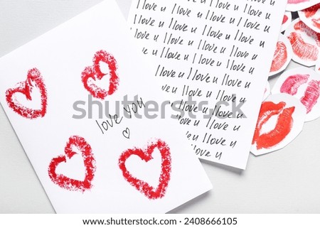 Greeting cards with text I LOVE YOU and lipstick kiss marks on grey background, closeup. Valentine's Day celebration