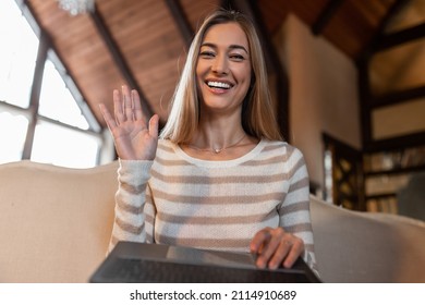 Greeting Concept. Portrait of excited adult woman waving hello with hand looking at camera, using laptop at home office. Cheerful lady saying hi or goodbye during video call, webcam view - Powered by Shutterstock