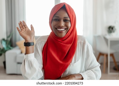 Greeting Concept. Portrait Of Happy Black Muslim Woman Waving Hello And Smiling At Camera, Using Laptop At Home Office. Positive Female Saying Hi During Video Call