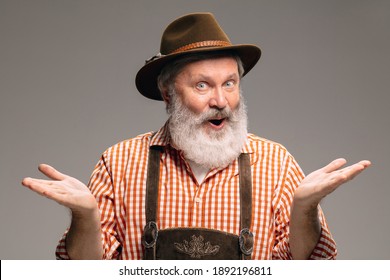 Greeting. Happy senior man dressed in traditional Austrian or Bavarian costume gesturing with on grey studio background. Copyspace. The celebration, oktoberfest, festival, traditions concept.