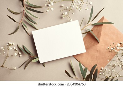 Greeting or invitation card mockup with craft paper envelope, eucalyptus and gypsophila twigs. Card mockup with copy space on beige background. - Shutterstock ID 2034304760