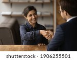 Greetings, you are hired. Happy young indian female successful job seeker shake hand of male hr manager being accepted on vacant place. Diverse business partners handshake close deal come to agreement