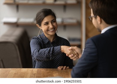 Greetings, you are hired. Happy young indian female successful job seeker shake hand of male hr manager being accepted on vacant place. Diverse business partners handshake close deal come to agreement