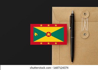 Grenada flag on craft envelope letter and black pen background. National invitation concept. Invitation for education theme.