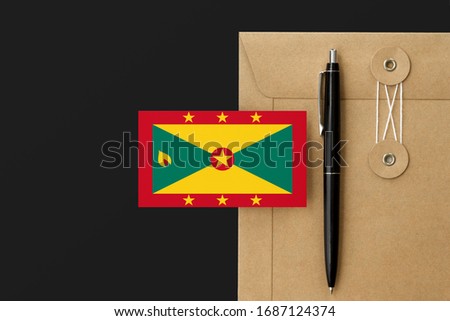 Grenada flag on craft envelope letter and black pen background. National invitation concept. Invitation for education theme.