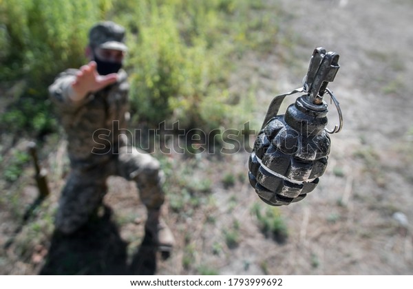Grenade\
in flight with safety pin. A soldier in a mask threw a grenade, top\
view, focus on the grenade. F1 grenade in\
flight.