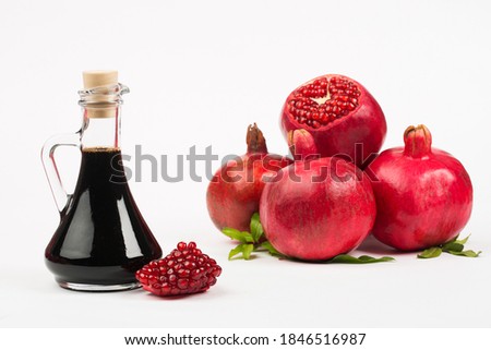 Grenadine in bottle and pomegranates on white background