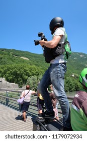 Grenoble, France – June 10, 2017: Photography Depicting A Professionnal Photograph Climbing On A Motorcycle To Take A Picture During The Cycling Event 'Le Critérium Du Dauphiné 2017'