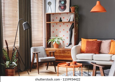 Grey Armchair Next To Lamp In Orange Vintage Living Room Interior With Sofa Next To Cabinet