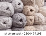 Grey and beige balls of yarn in storage. Warm wool yarn background. Knitting hobby. Row of grey and beige yarn. Handiwork store. Knit background. Handcraft concept. Knit pattern.