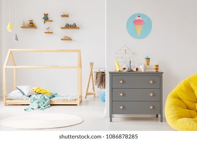 Grey cabinet against white wall with poster in modern child's room interior with wooden bed