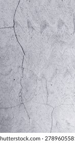 Grey cement plaster wall with multiple diagonal cracks and visible trowel swirl application marks across entire surface, vertical close up full frame. Dark dust spots and varied grey tone visible on weathered plaster texture. Cracked grey plaster wall suitable for grunge, concrete, and urban decay background use.