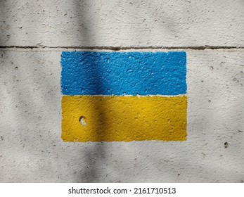Grey cement wall with national flag of Ukraine country. Blue yellow color stripes painted on rough limestone wall surface. Closeup Ukrainian flag drawn on stone texture with copy space