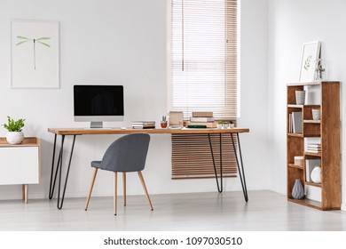 Grey Chair At Desk With Computer Monitor In Minimal Workspace Interior With Poster. Real Photo