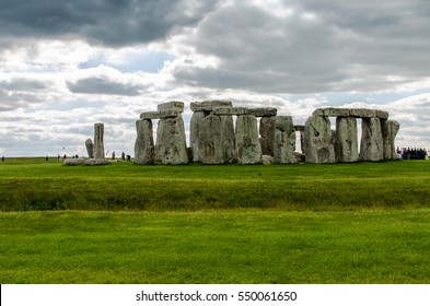 Grey Clouds Hover Above Stonehenge In Springtime As Visitors Make It A Busy Day