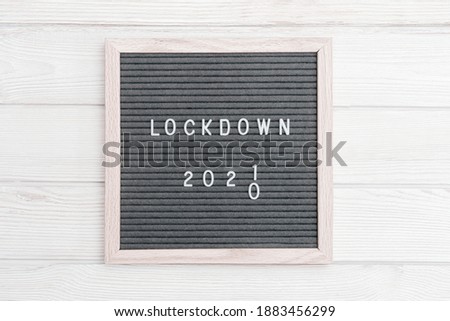 Grey colored Flatlay letter board with message text lockdown 2021 and protective face mask. Lock down loading concept. Social media content.