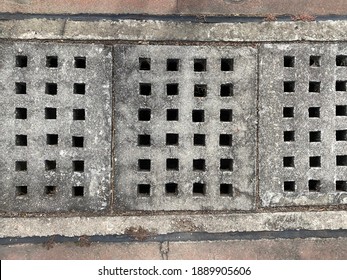 Grey Concrete Storm Drain Covers With Square Holes.