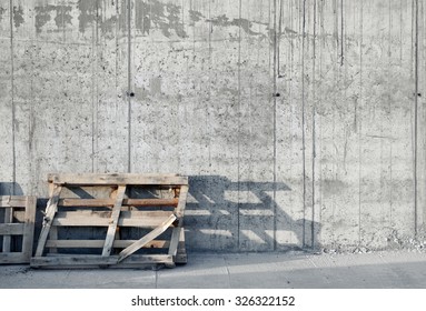 Grey Concrete Wall With Wood Palette. Construction Site. Sunset.