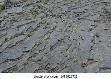 Grey Craggy Rough Sedimentary Basin Rock Layers And Flagstones On Cliff Edge