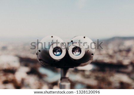 Grey device for sightseeing, stationary viewing binoculars, viewing binoculars with bill acceptor, or binocular with view of Tbilisi, georgian capital on background