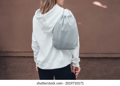 Grey Drawstring Pack Template, Mockup Of Bag For Sport Shoes On Woman's Shoulder, Back View. Lifestyle, Cropped.