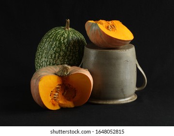 Grey earthen  pot and two different pumpkins