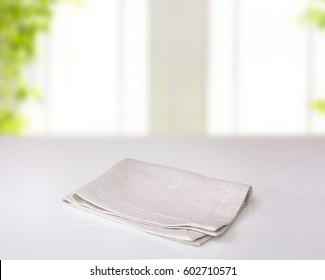 Grey Folded Kitchen Cloth On White Table Indoor Background.Empty Napkin Food Advertisement Concept.