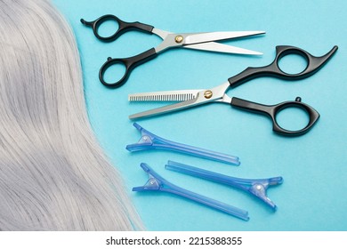 Grey Hair And Hairdressing Hair Clips, Scissors For Cutting. Creating Beautiful Hairstyles. Blue Background. Top View. Flat Lay.