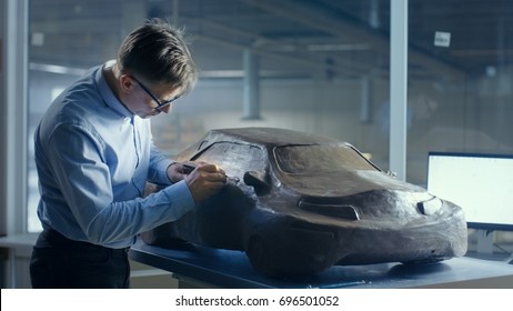 Grey Haired Automotive Designer Sculpts Futuristic  Car Model From Plasticine Clay With Wire. He Works In A Special Studio Located In A Large Car Factory.