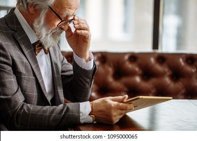 Grey Haired Fashion Old Man In Glasses Using IPad At Home. Closeup Side View Photo