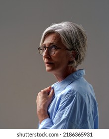 Grey Haired Mature Woman Studio Shot In Low Light. Dramatic Portrait Of An Mature Grey Haired Woman. Sad Lonely Mature Woman. Senior Woman Thinking In Low Light.