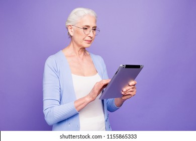 Grey Haired Old Serious Business Woman Wearing Glasses, Reading Browsing Using Tablet, Typing Letter. Isolated Over Violet Purple Background