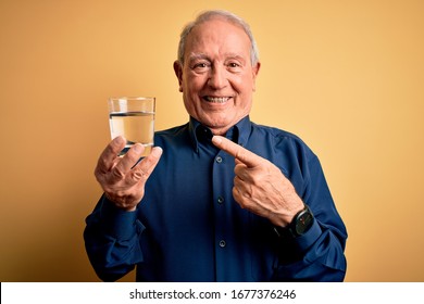 Grey Haired Senior Man Drinking A Fresh Glass Of Water Over Yellow Isolated Background Very Happy Pointing With Hand And Finger