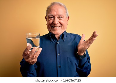 Grey Haired Senior Man Drinking A Fresh Glass Of Water Over Yellow Isolated Background Very Happy And Excited, Winner Expression Celebrating Victory Screaming With Big Smile And Raised Hands