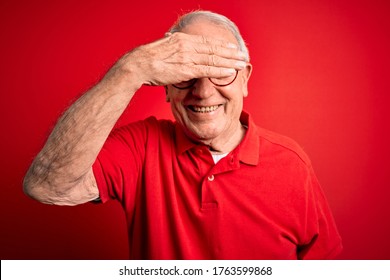 Grey haired senior man wearing glasses and casual t-shirt over red background smiling and laughing with hand on face covering eyes for surprise. Blind concept. - Powered by Shutterstock