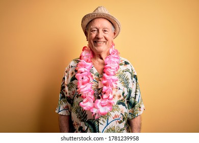 Grey Haired Senior Man Wearing Summer Hat And Hawaiian Lei Over Yellow Background With A Happy And Cool Smile On Face. Lucky Person.