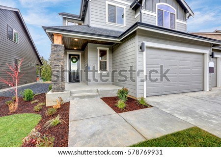 Grey home with wood siding, stone column, covered porch and two  garage spaces. Northwest, USA