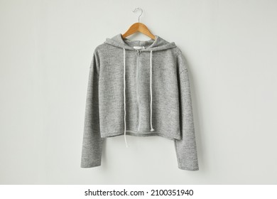 A Grey Hoodie Front view.gray toned clothes hanging on the white wall