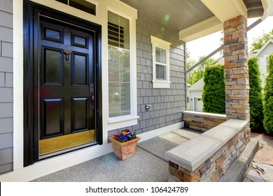 Grey House Exterior With Black Door And Stone Wall.