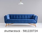 Grey interior with stylish upholstered blue sofa and lamp