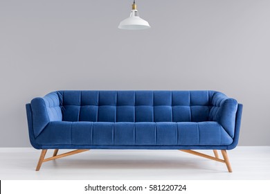 Grey interior with stylish upholstered blue sofa and lamp - Shutterstock ID 581220724