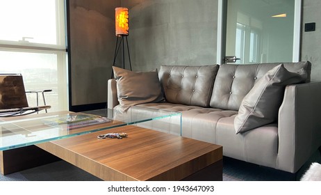 Grey Leather Sofa In Front Of Grey Wall And Orange Lamp.