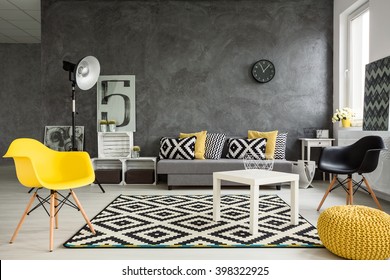 Grey living room with sofa, chairs, standing lamp, small table, yellow details and pattern decorations in black and white 