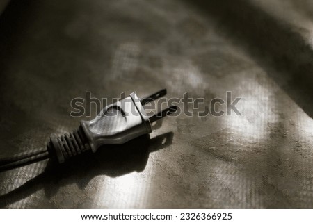 A grey male plug type A in natural, low key lighting. Electric device, electric accessory, socket, power concept.