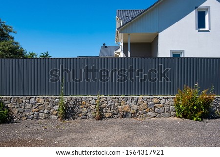 Grey metal corrugated fence in front of a residential building. Texture of profiled metal.