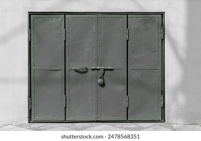 Grey painted metal door. texture for background. Gray door with lock. window sheet metal gate and doors. Vintage industrial metal door gate with locking system. Old sheet iron. grey wall