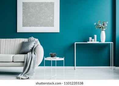 Grey painting on the green wall, white coffee table, desk, and blanket on the sofa in a modern living room interior - Shutterstock ID 1101235538