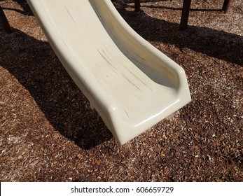 Grey Plastic Playground Slide With Scuff Marks And Wood Chips