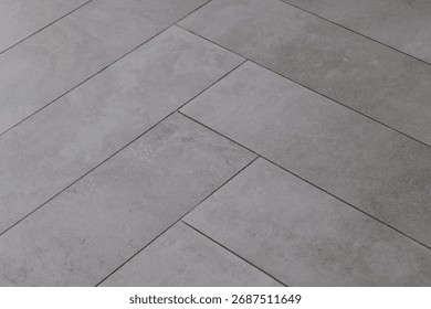 Grey rectangular tile texture in herringbone pattern imitating natural stone or concrete, decorative ceramic surface
